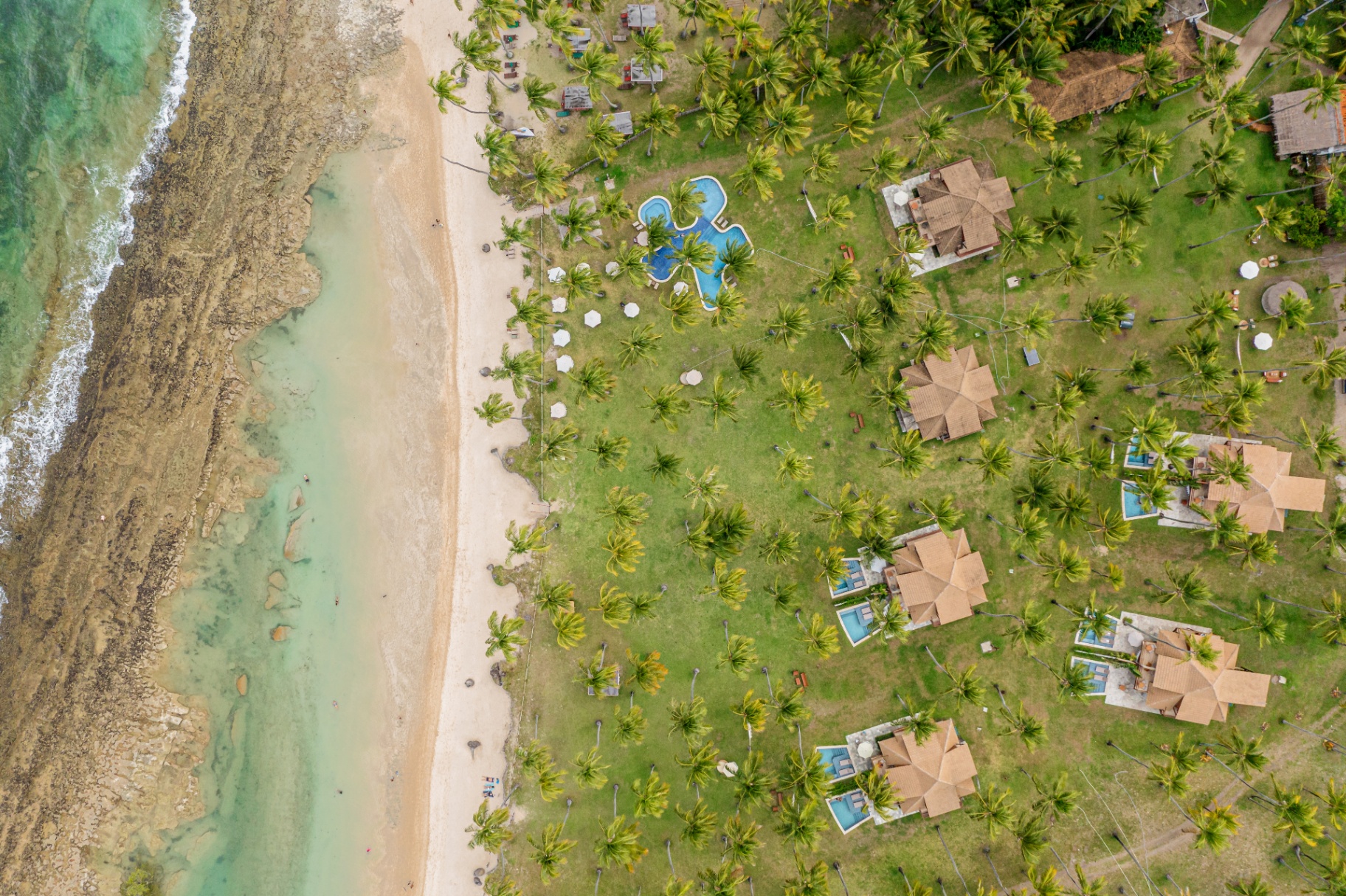 Vista aérea do Pontal dos Carneiros com bungalows, piscina e a praia