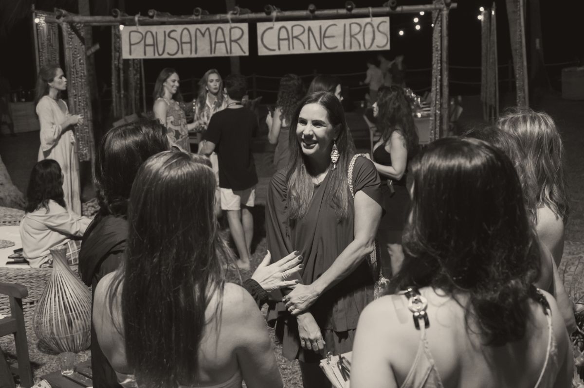 Christiana Rocha recebendo as convidadas sob o letreiro PAUSAMAR